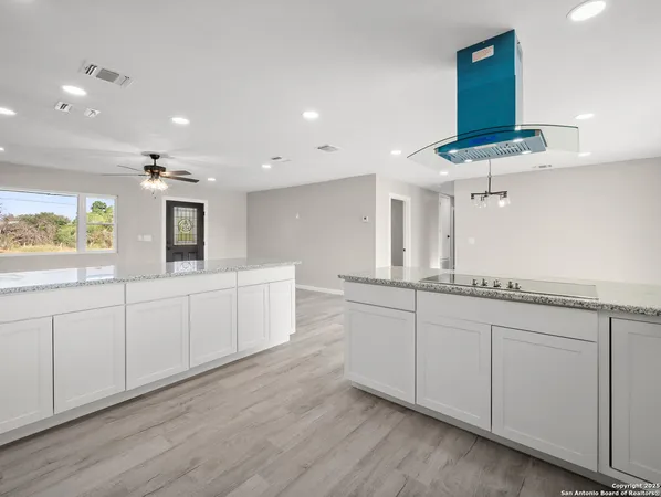 a large white kitchen with stainless steel appliances granite countertop a white cabinets and a wooden floor