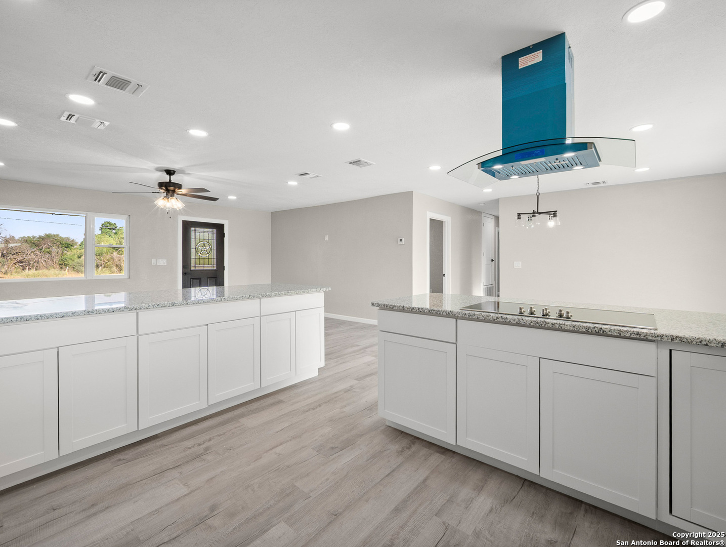 19551 Farm To Market Road 463 Devine, TX 78016 - Photo 7 of 27 a large white kitchen with stainless steel appliances granite countertop a white cabinets and a wooden floor