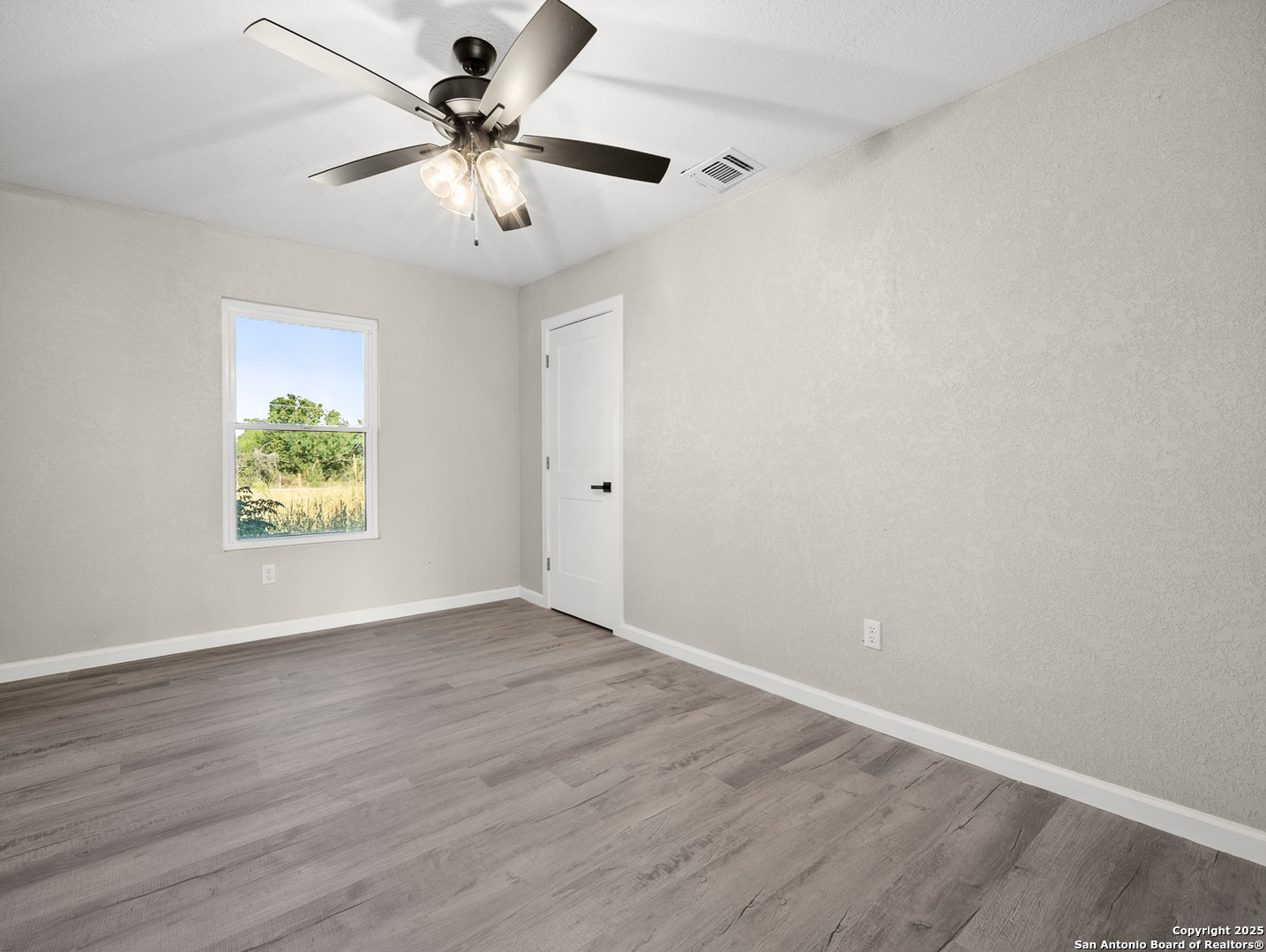 19551 Farm To Market Road 463 Devine, TX 78016 - Photo 9 of 27 wooden floor in an empty room with a window