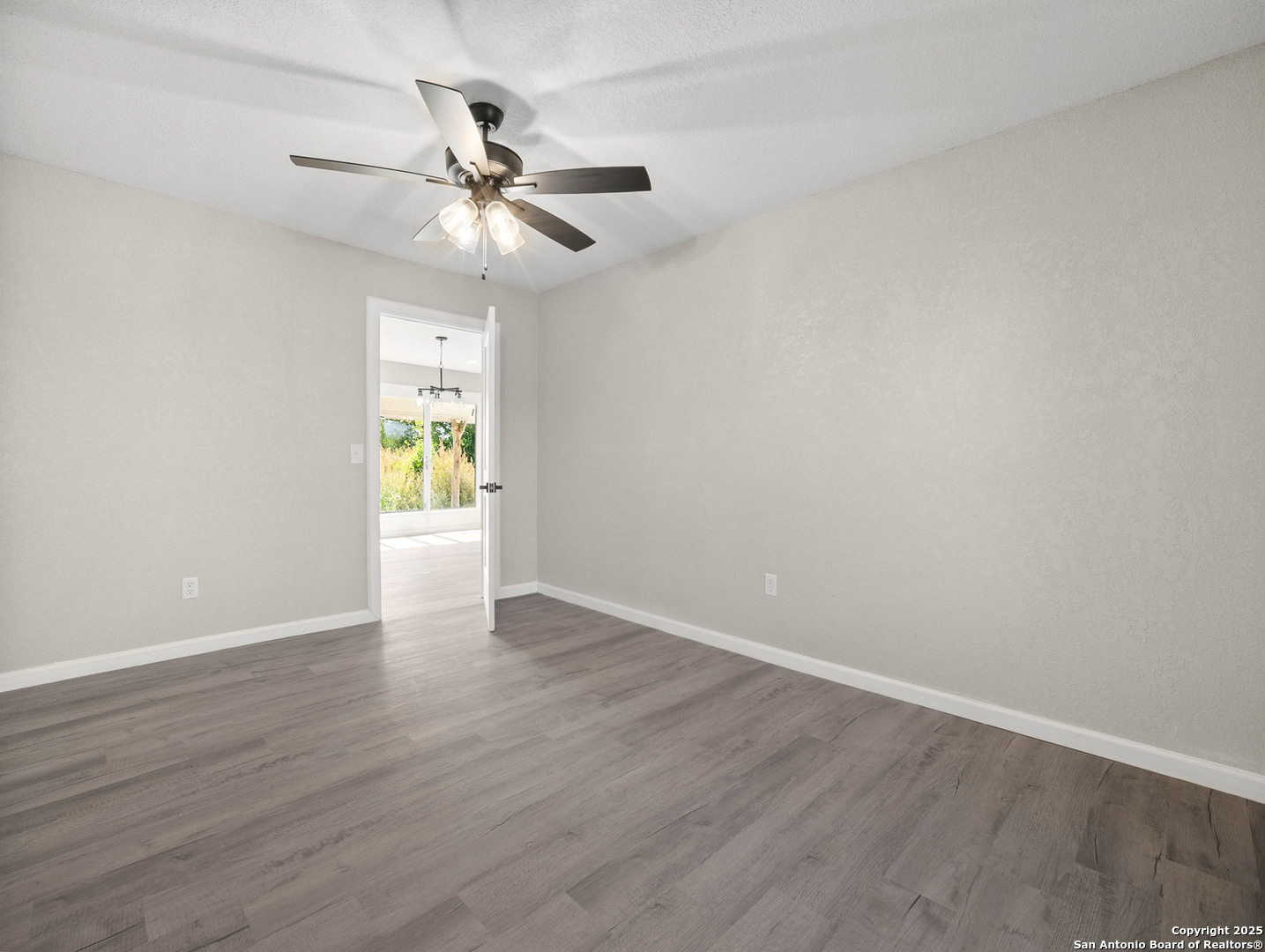 19551 Farm To Market Road 463 Devine, TX 78016 - Photo 10 of 27 wooden floor in an empty room with a window