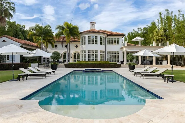 a view of a house with a yard and palm trees