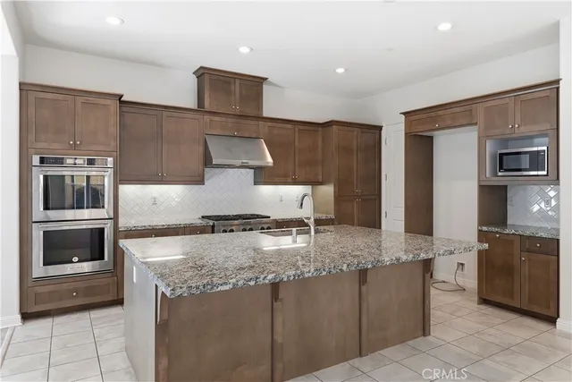 a kitchen with stainless steel appliances granite countertop a stove a sink and a microwave