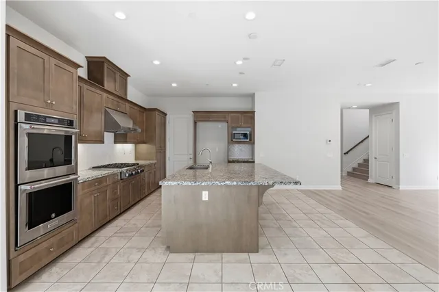 a large kitchen with stainless steel appliances granite countertop a refrigerator and a stove