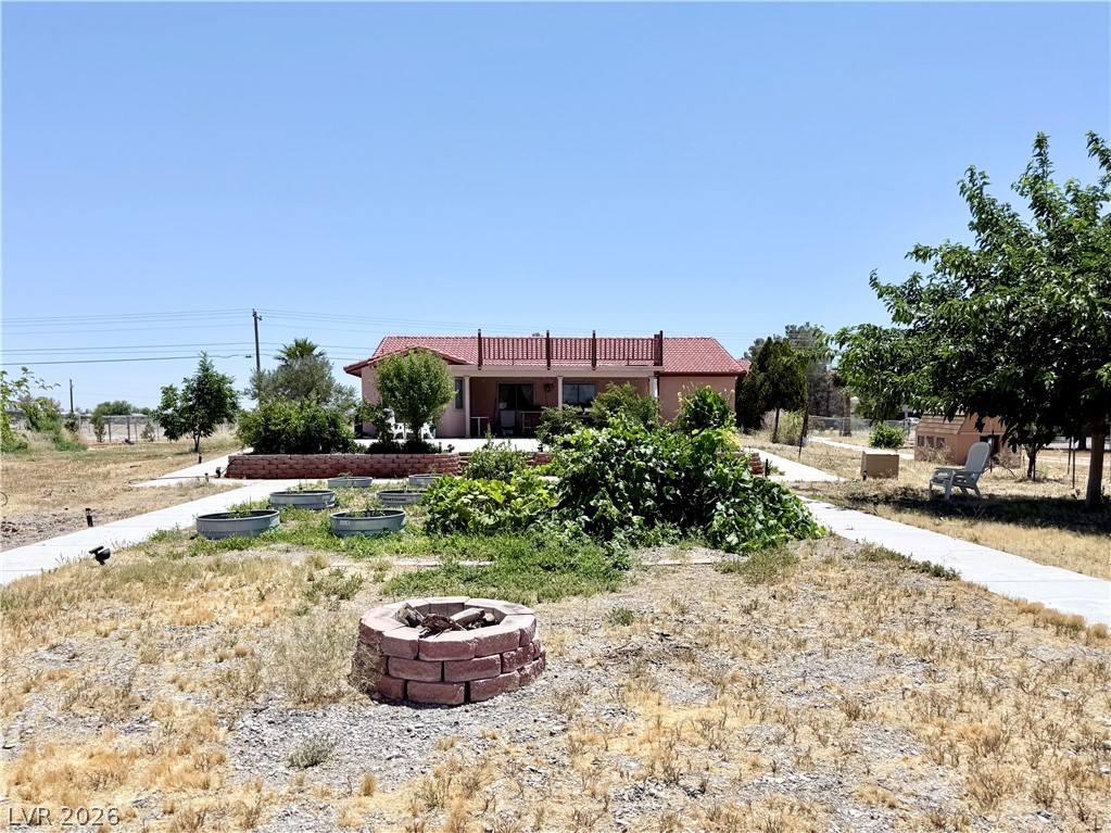 1220 East Gamebird Road Pahrump, NV 89048 - Photo 26 of 49 A spacious yard boasts a brick fire pit, ample gardening space, and a well-maintained walkway leading to the house.
