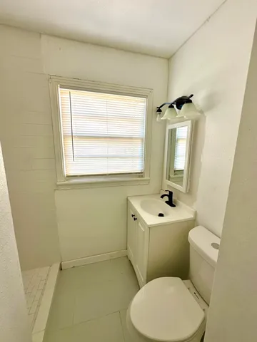 a bathroom with a sink mirror toilet and window