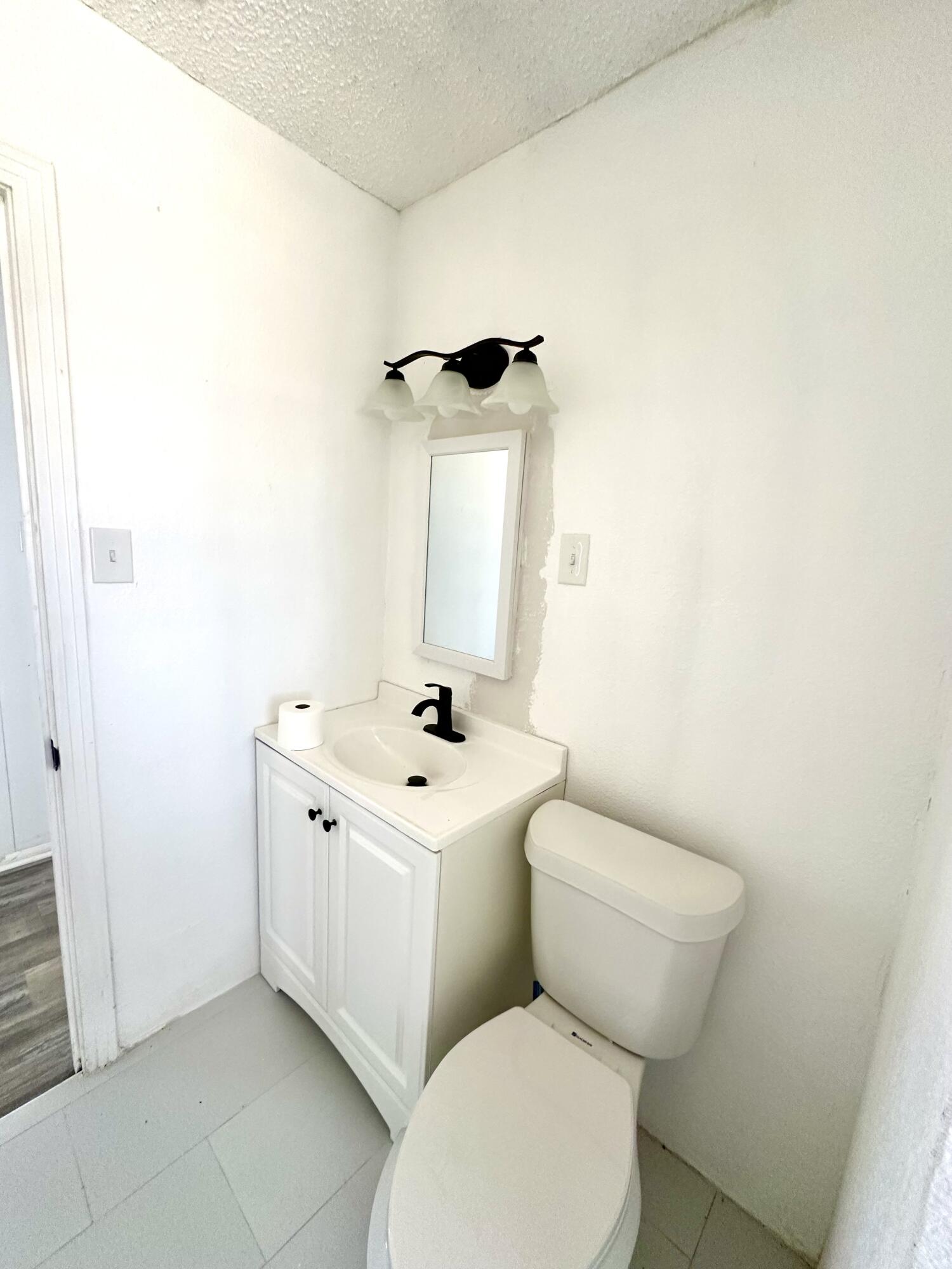 1827 8th Street Levelland, TX 79336 - Photo 17 of 25 a bathroom with a toilet a sink and mirror