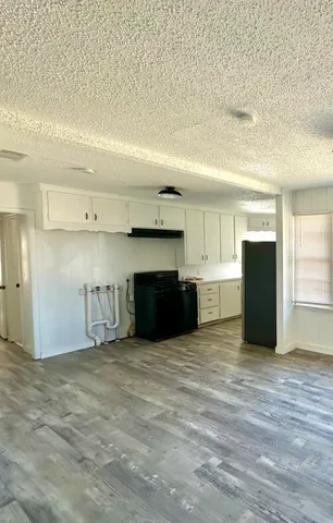 a view of an empty room with kitchen and a window