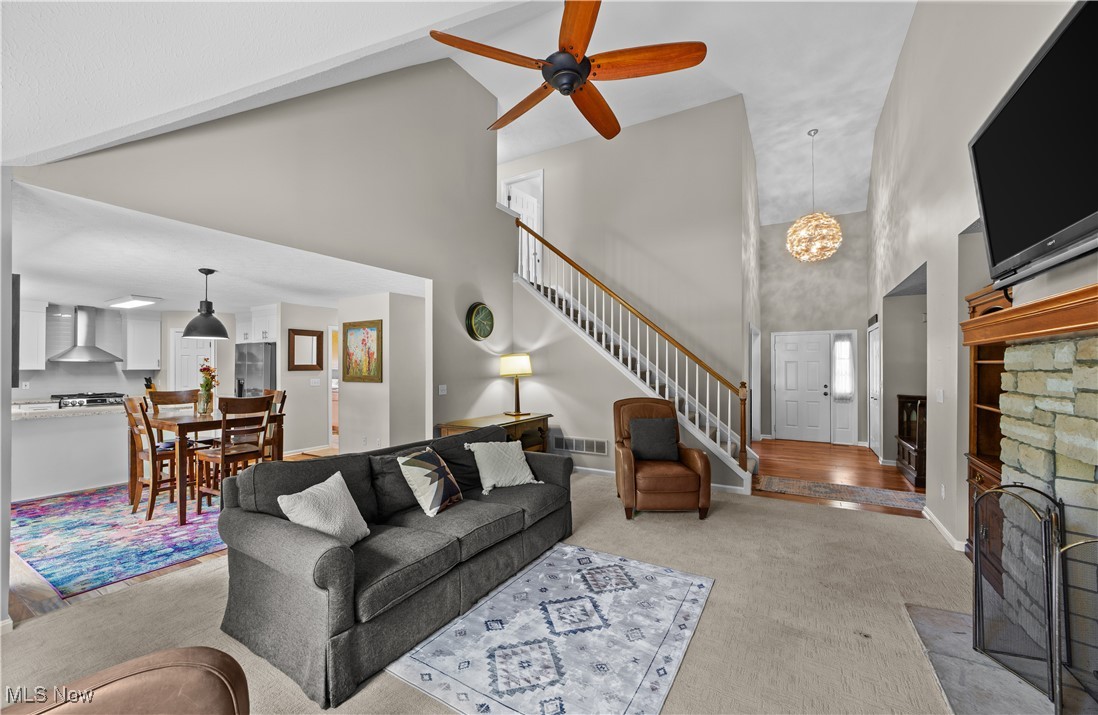 30825 Cannon Road Solon, OH 44139 - Photo 6 of 49 Living room featuring a towering ceiling, a fireplace, carpet, a chandelier, and stairs