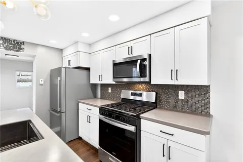 a kitchen with stainless steel appliances a refrigerator a sink dishwasher a stove a microwave oven with cabinets and wooden floor