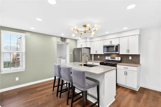 a kitchen with stainless steel appliances a kitchen island hardwood floor sink stove dining table and chairs