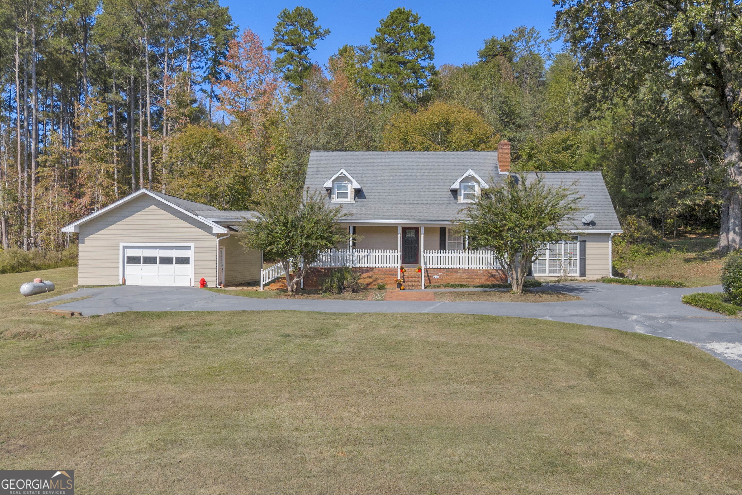 a front view of house with yard and trees in the background