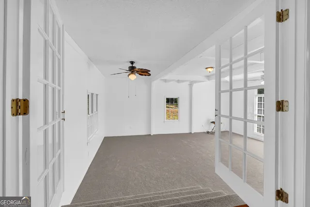 a view of an empty room with a window and a ceiling fan