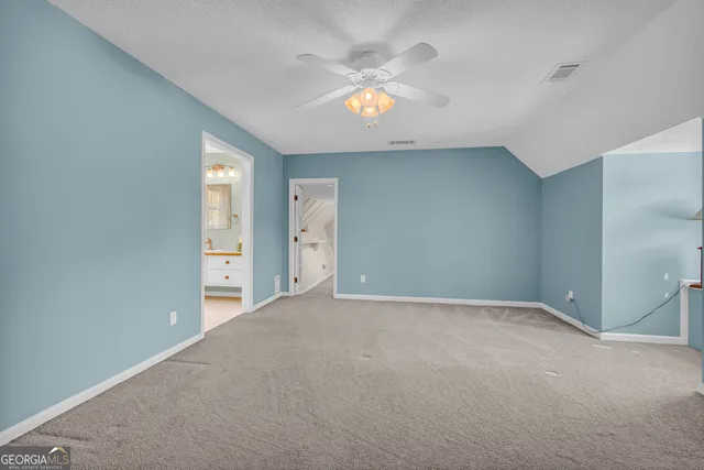 a view of an empty room with chandelier fan