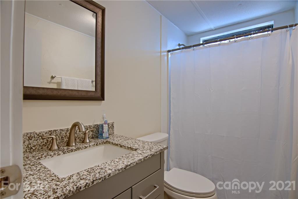 73 Church Road Fairview, NC 28730 - Photo 19 of 45 a bathroom with a granite countertop sink toilet a mirror a vanity and shower