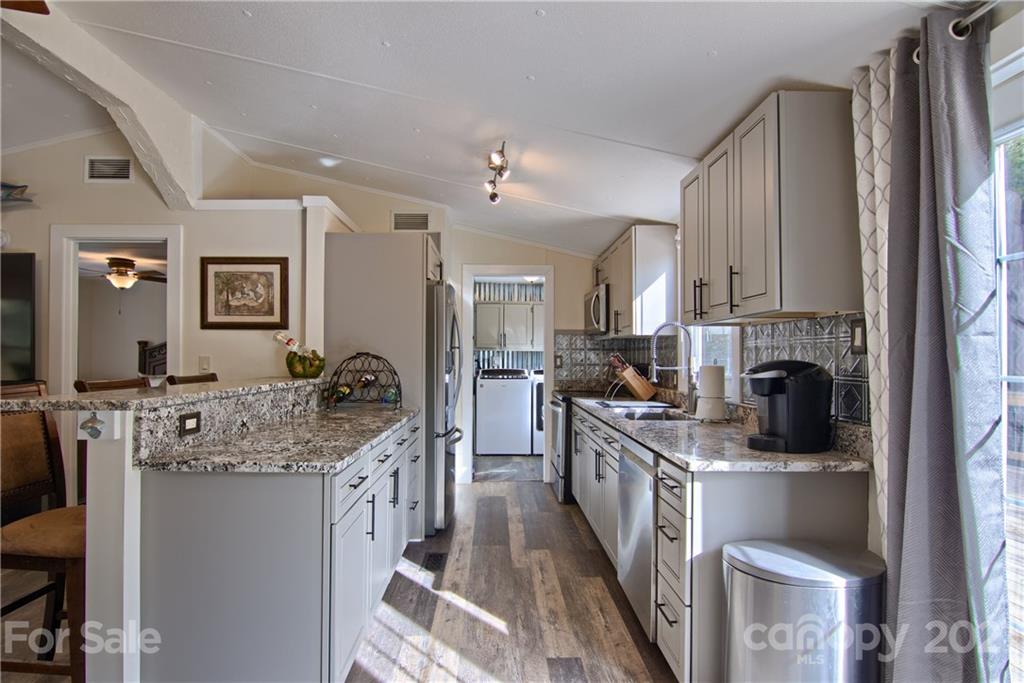 73 Church Road Fairview, NC 28730 - Photo 5 of 45 a kitchen with stainless steel appliances granite countertop a stove top oven a sink dishwasher a refrigerator and a dining table with wooden floor