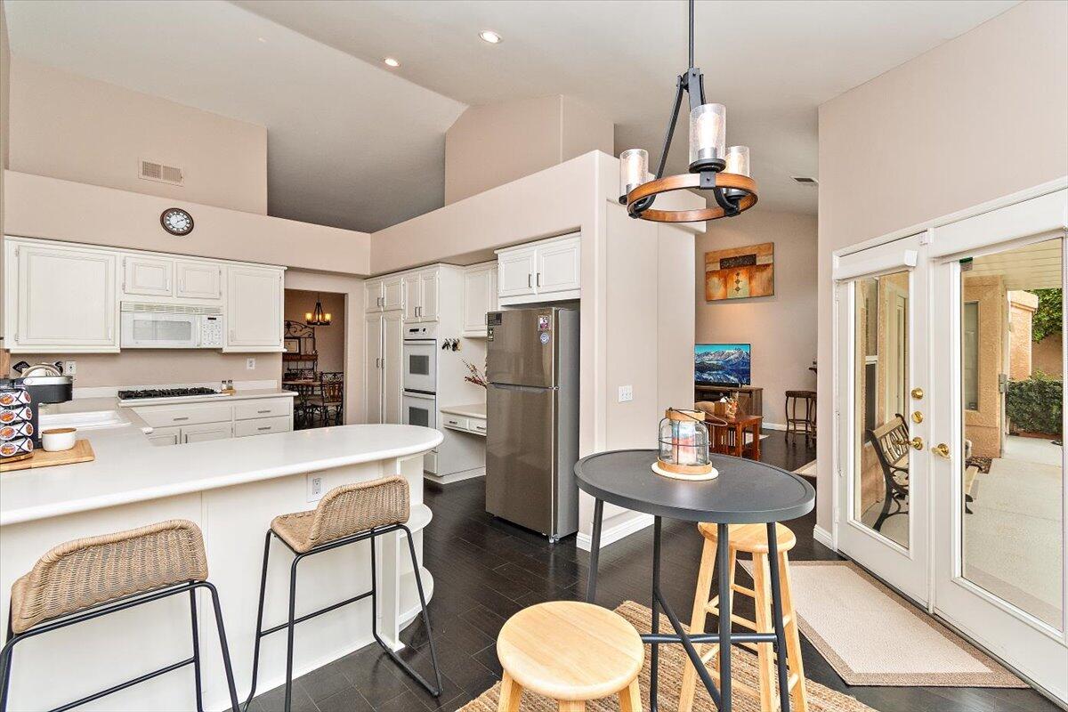 45510 Desert Fox Drive La Quinta, CA 92253 - Photo 20 of 49 a kitchen with stainless steel appliances kitchen island granite countertop a dining table chairs and a refrigerator