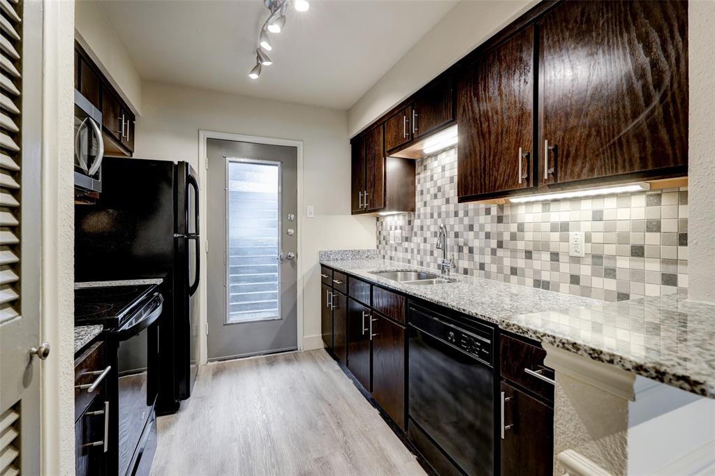 a kitchen with granite countertop stainless steel appliances a sink stove top oven and refrigerator