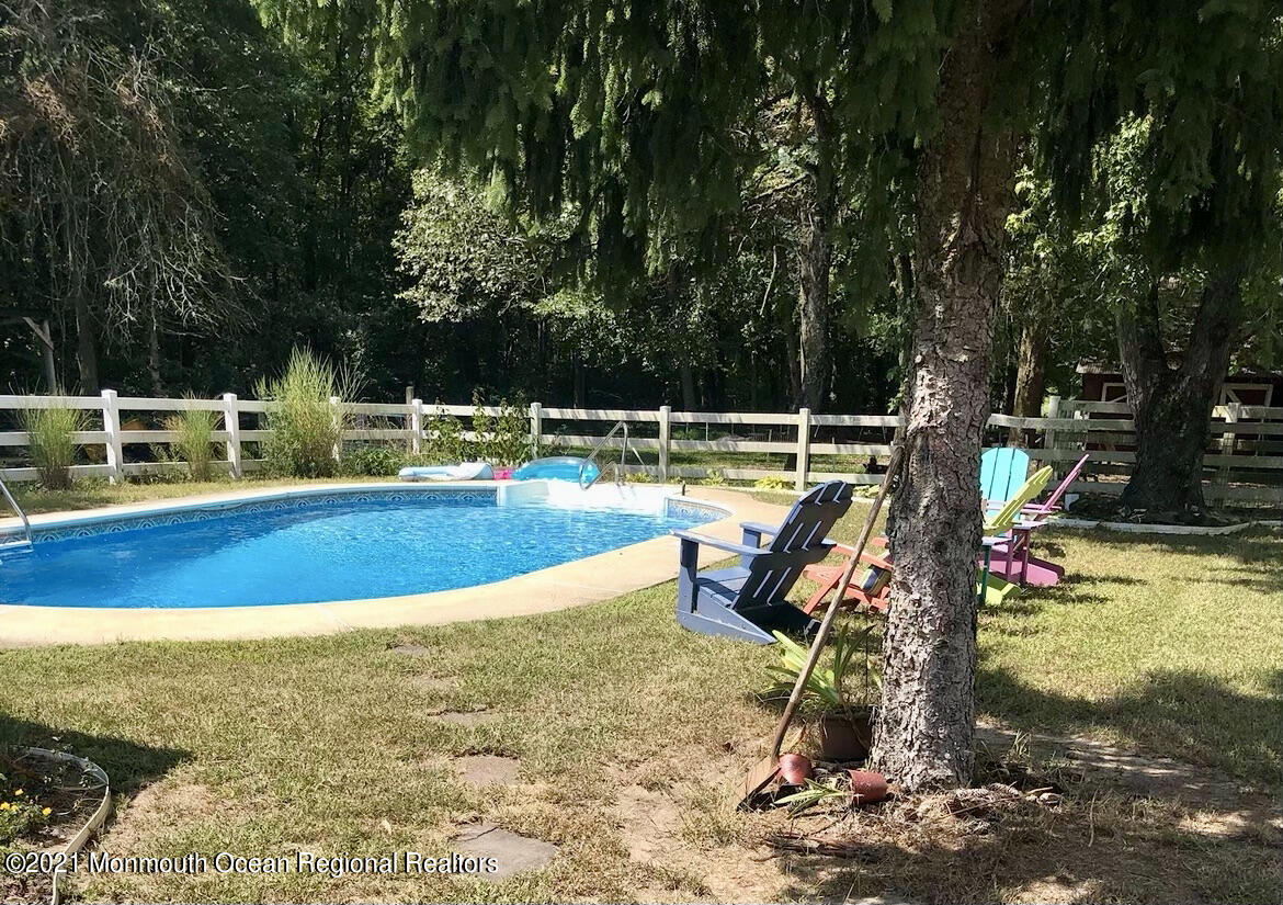866 Monmouth Road Cream Ridge, NJ 08514 - Photo 29 of 39 a view of a swimming pool with a bench and trees in the background