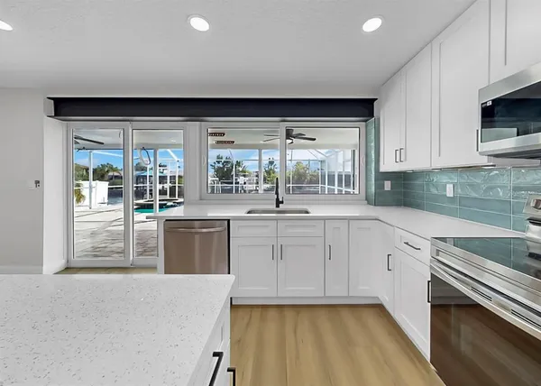 a large white kitchen with kitchen island a sink dishwasher a stove and a refrigerator with wooden floor
