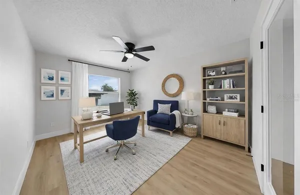an empty room with wooden floor ceiling fan and windows