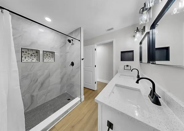 an empty room with wooden floor ceiling fan and windows