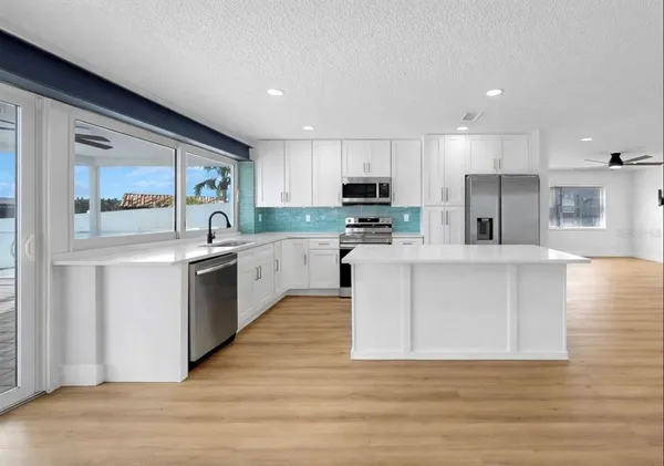 a kitchen with stainless steel appliances granite countertop a sink stove refrigerator and cabinets