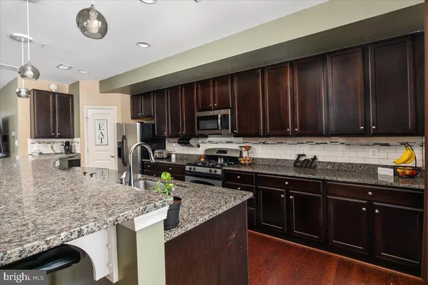 a kitchen with granite countertop stainless steel appliances a stove sink microwave and cabinets