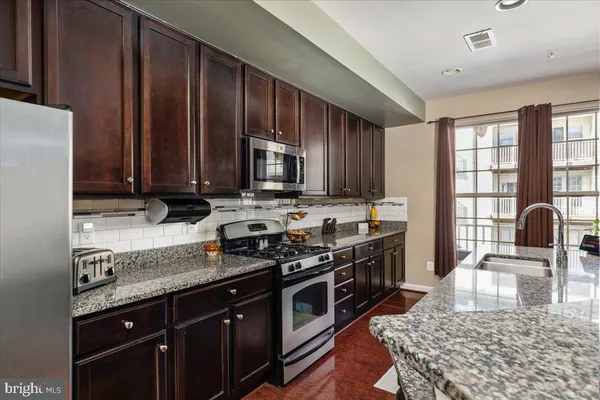 a kitchen with stainless steel appliances granite countertop a stove a sink dishwasher a microwave oven with granite countertops and cabinets