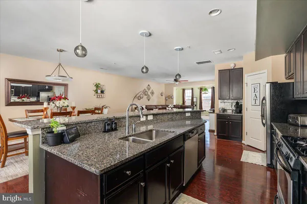 a kitchen with stainless steel appliances granite countertop a sink a stove and a wooden floors