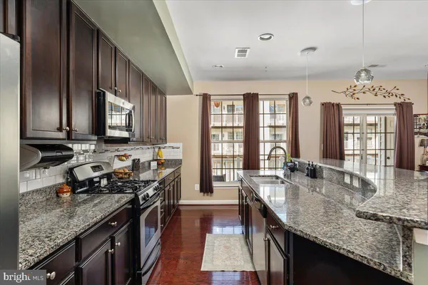 a kitchen with granite countertop stainless steel appliances a sink stove top oven and cabinets