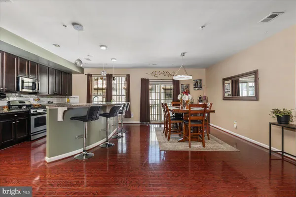 a kitchen with stainless steel appliances granite countertop a stove top oven a sink a dining table and chairs with wooden floor