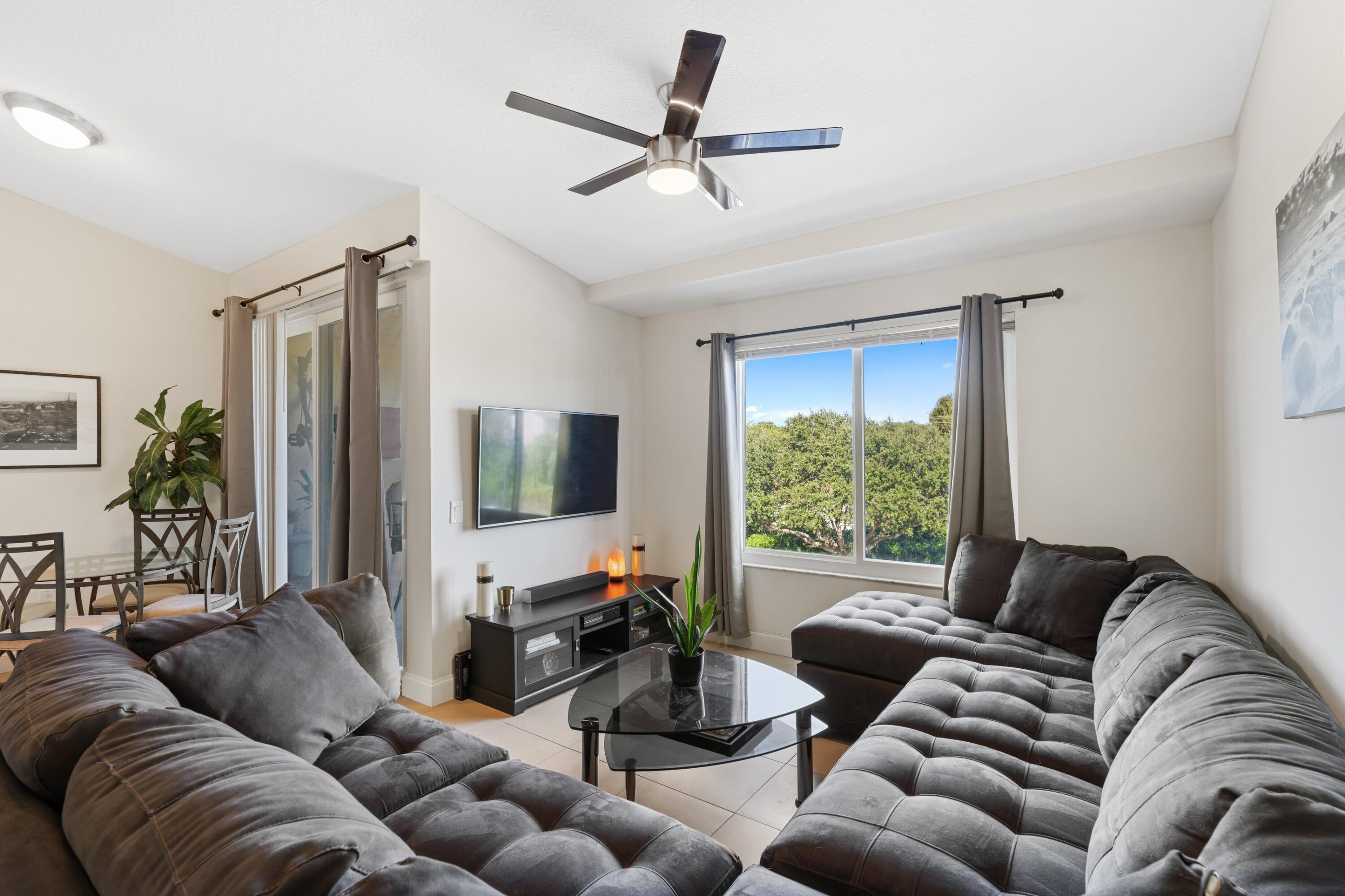 a living room with furniture ceiling fan and a large window