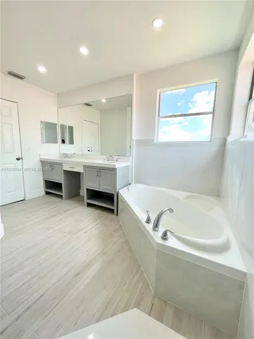 a bathroom with a tub a sink and a mirror