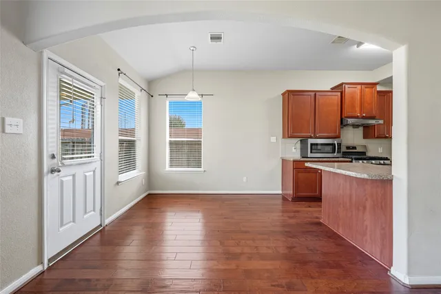 a kitchen with granite countertop a stove top oven a sink and a refrigerator