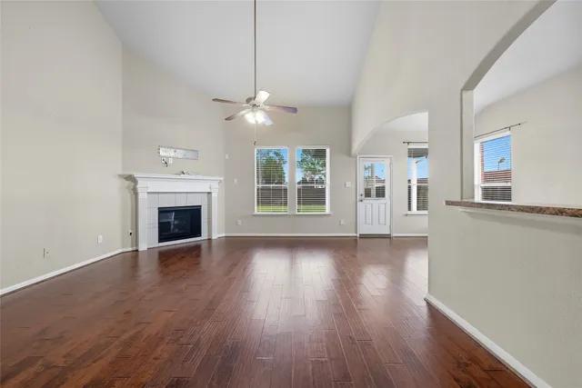 a view of an empty room with wooden floor fireplace and a window