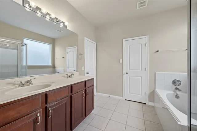 a spacious bathroom with a tub a double vanity sink and a mirror