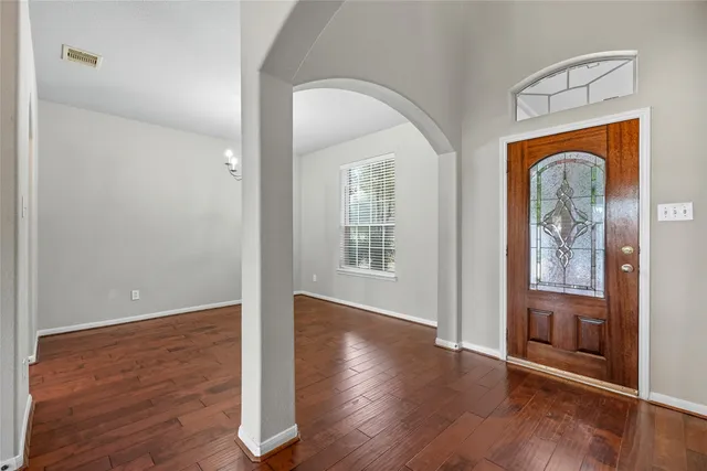an empty room with wooden floor mirror and windows