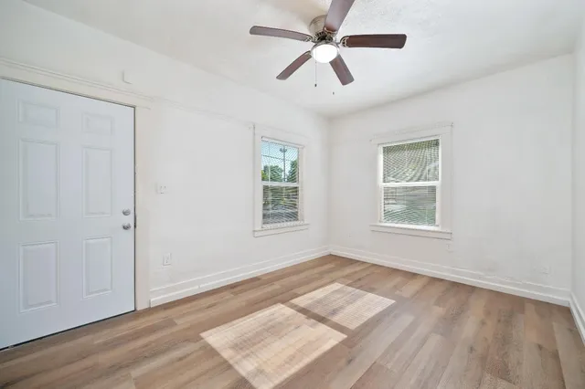 a view of an empty room with wooden floor and a window