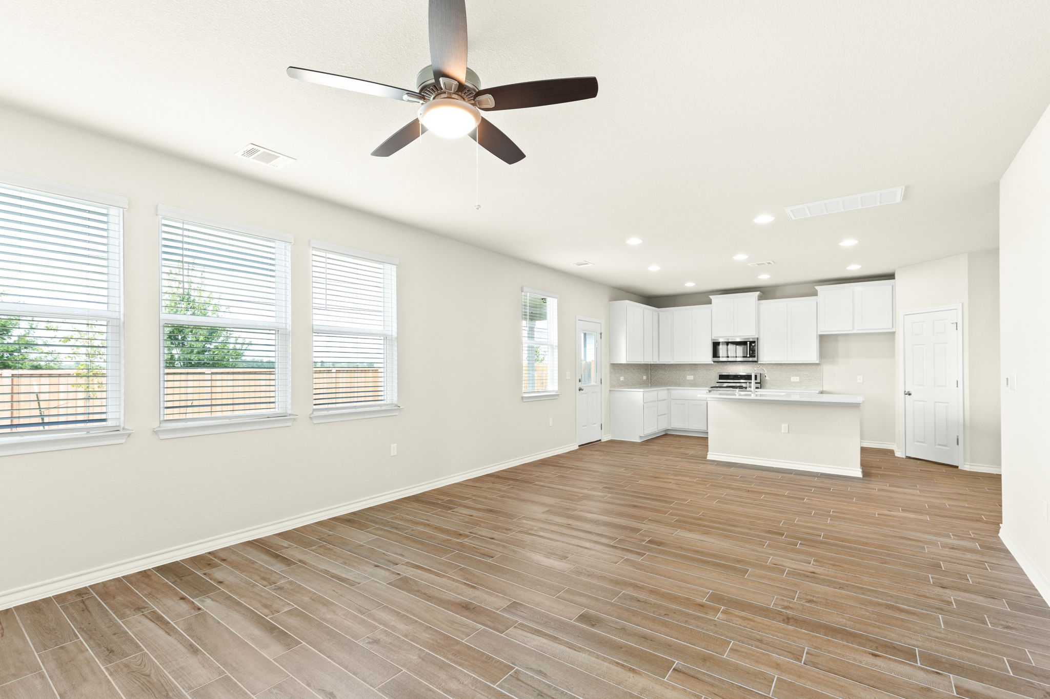 1624 Caballo Blanco Road Austin, TX 78725 - Photo 8 of 27 Wood-look flooring runs seamlessly through the open living area into the modern kitchen.