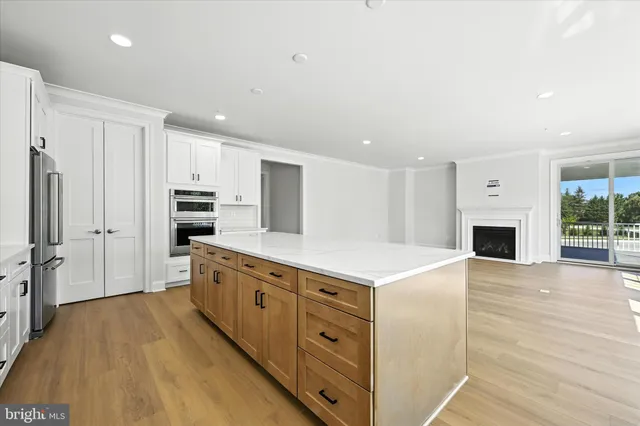 a large kitchen with stainless steel appliances a white cabinets and wooden floor