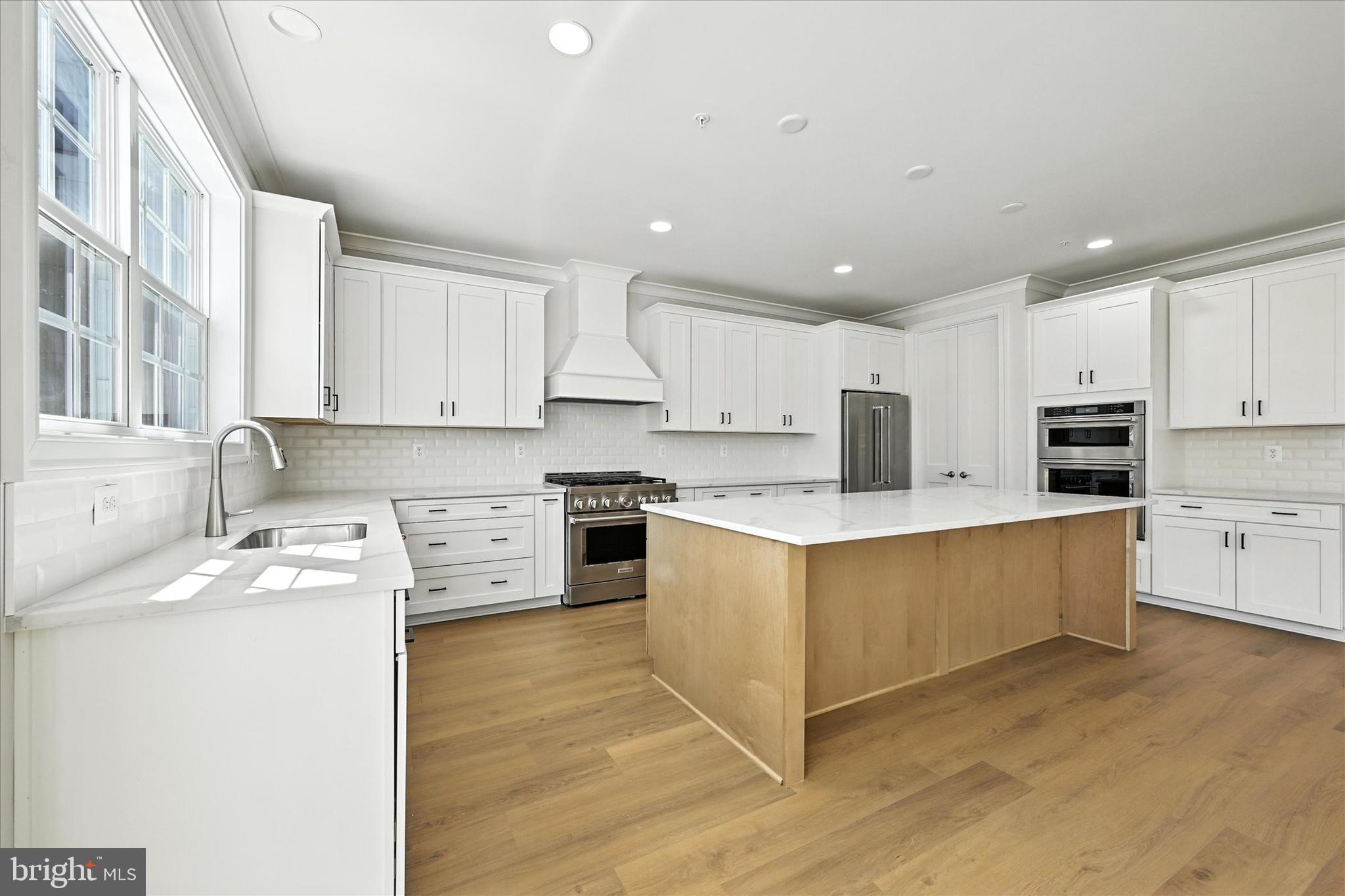 106 Villabrook Way Baltimore, MD 21212 - Photo 15 of 60 a large kitchen with stainless steel appliances granite countertop a stove a sink a refrigerator and white cabinets with wooden floor