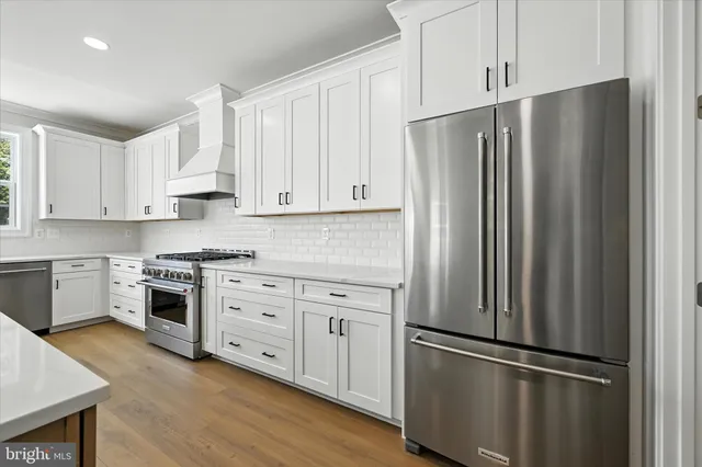 a kitchen with stainless steel appliances white cabinets and a refrigerator