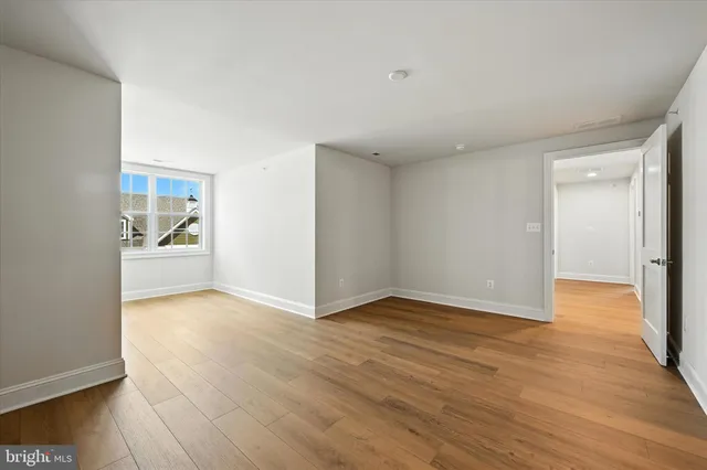 a view of an empty room with wooden floor and closet