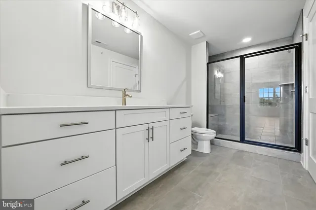 a bathroom with a bathtub shower sink vanity mirror and toilet