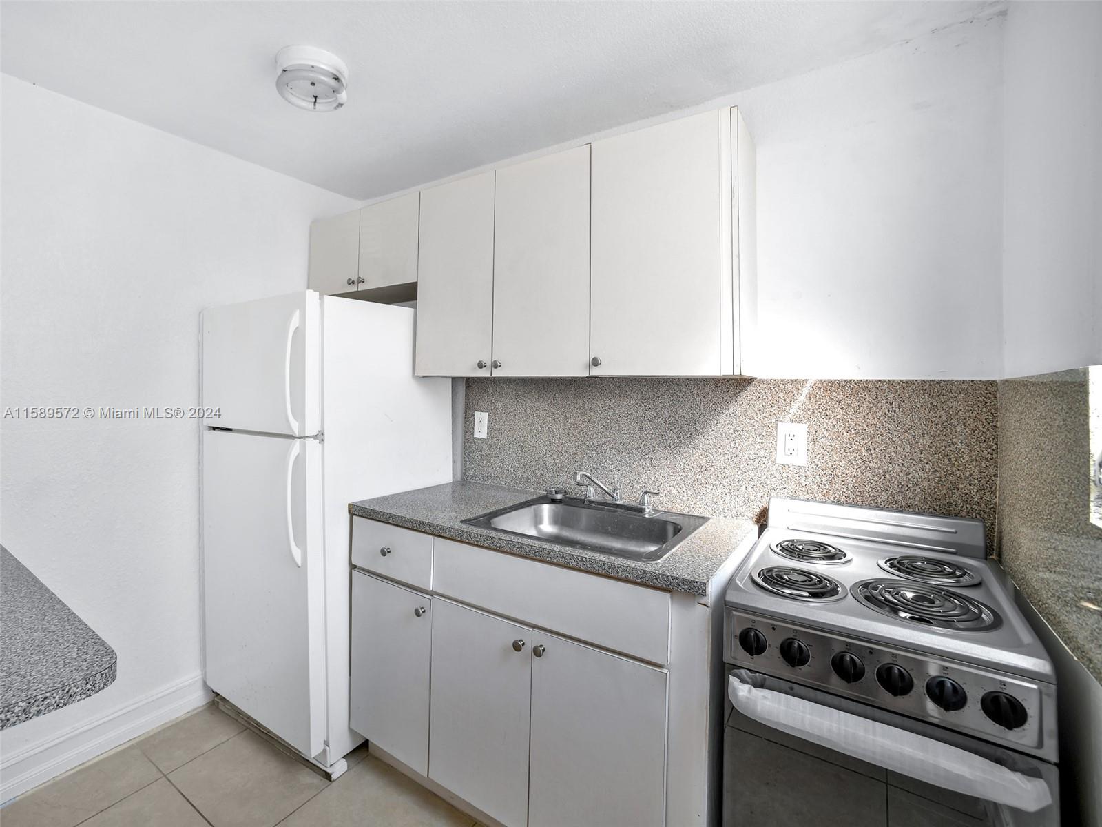 265 East 7th Street Hialeah, FL 33010 - Photo 14 of 28 a kitchen with stainless steel appliances granite countertop white cabinets stove top oven and sink