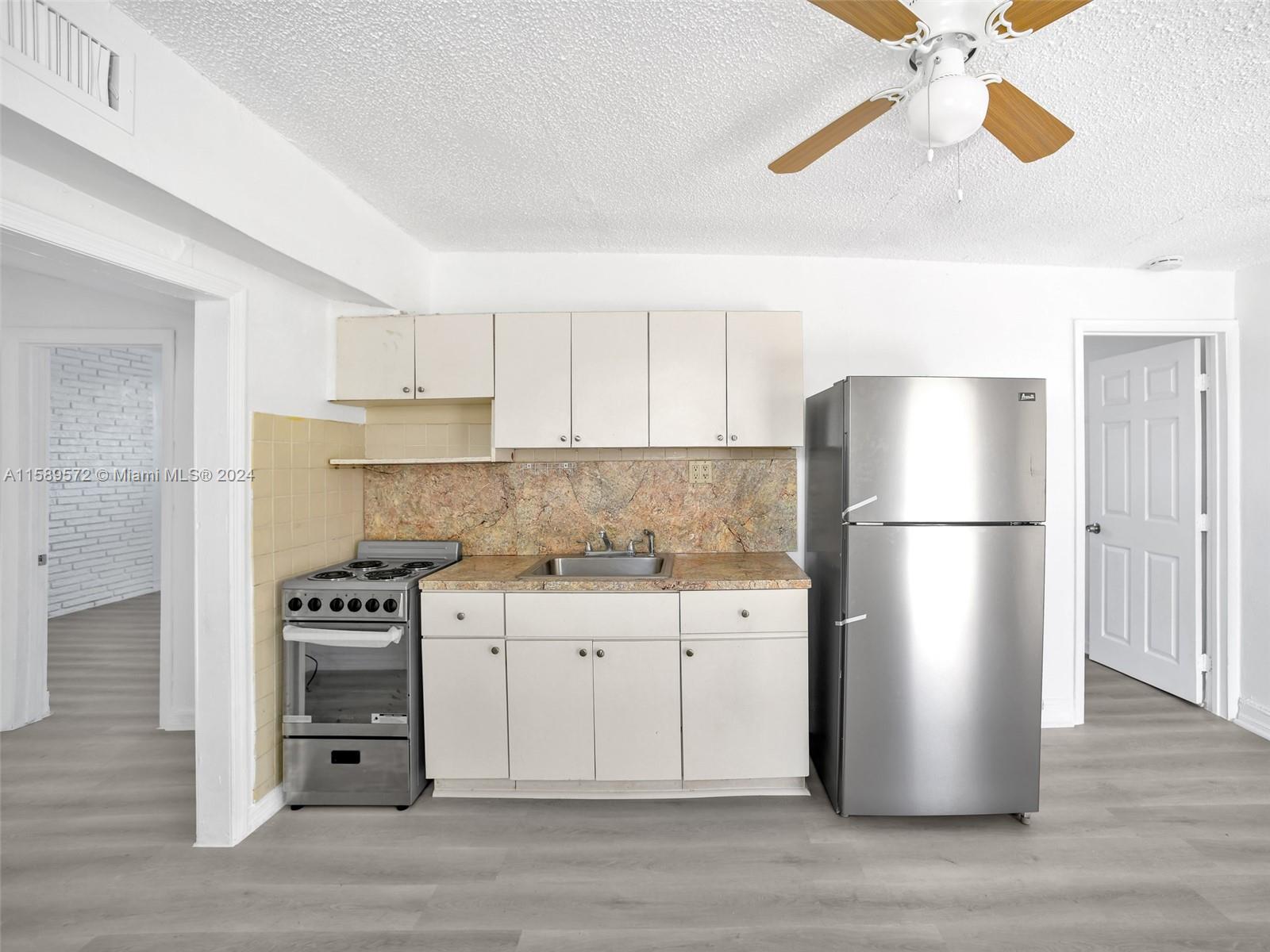 265 East 7th Street Hialeah, FL 33010 - Photo 17 of 28 a kitchen with a refrigerator and a stove top oven