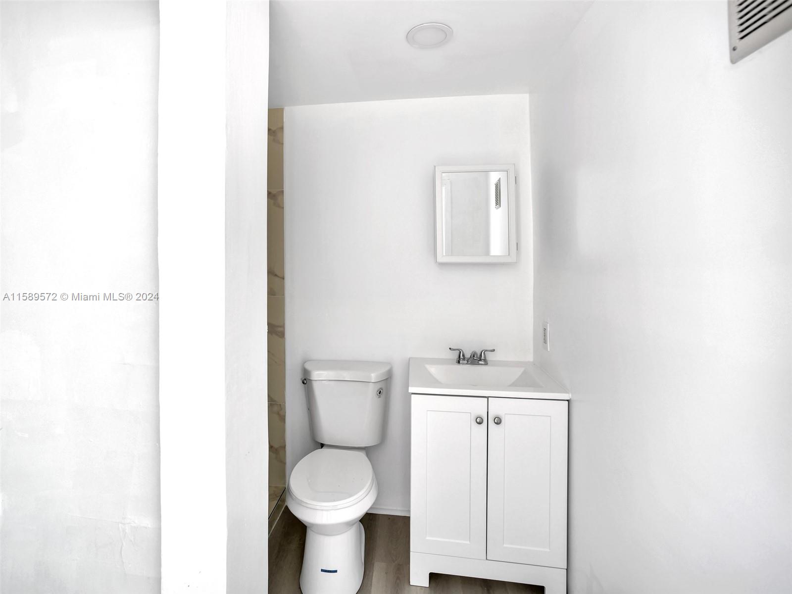 265 East 7th Street Hialeah, FL 33010 - Photo 21 of 28 a bathroom with a toilet a sink and mirror