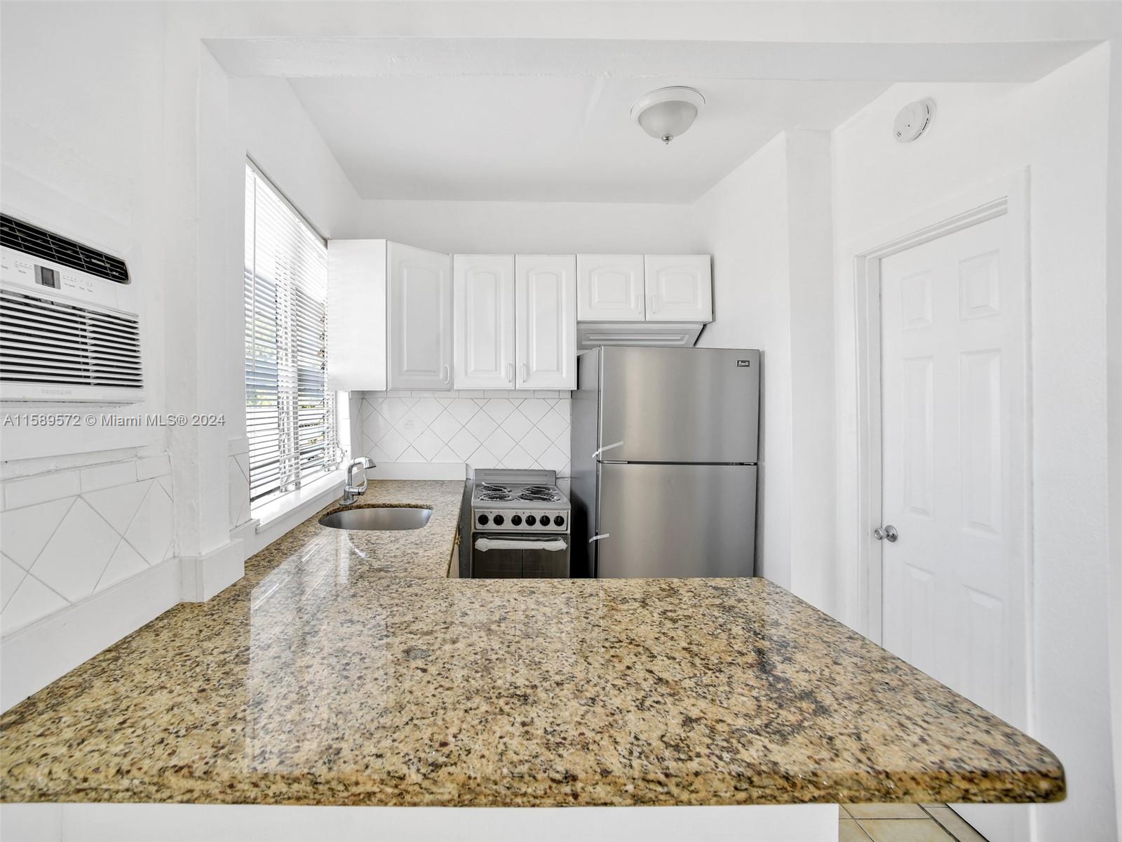 265 East 7th Street Hialeah, FL 33010 - Photo 6 of 28 a kitchen with a refrigerator and a stove top oven