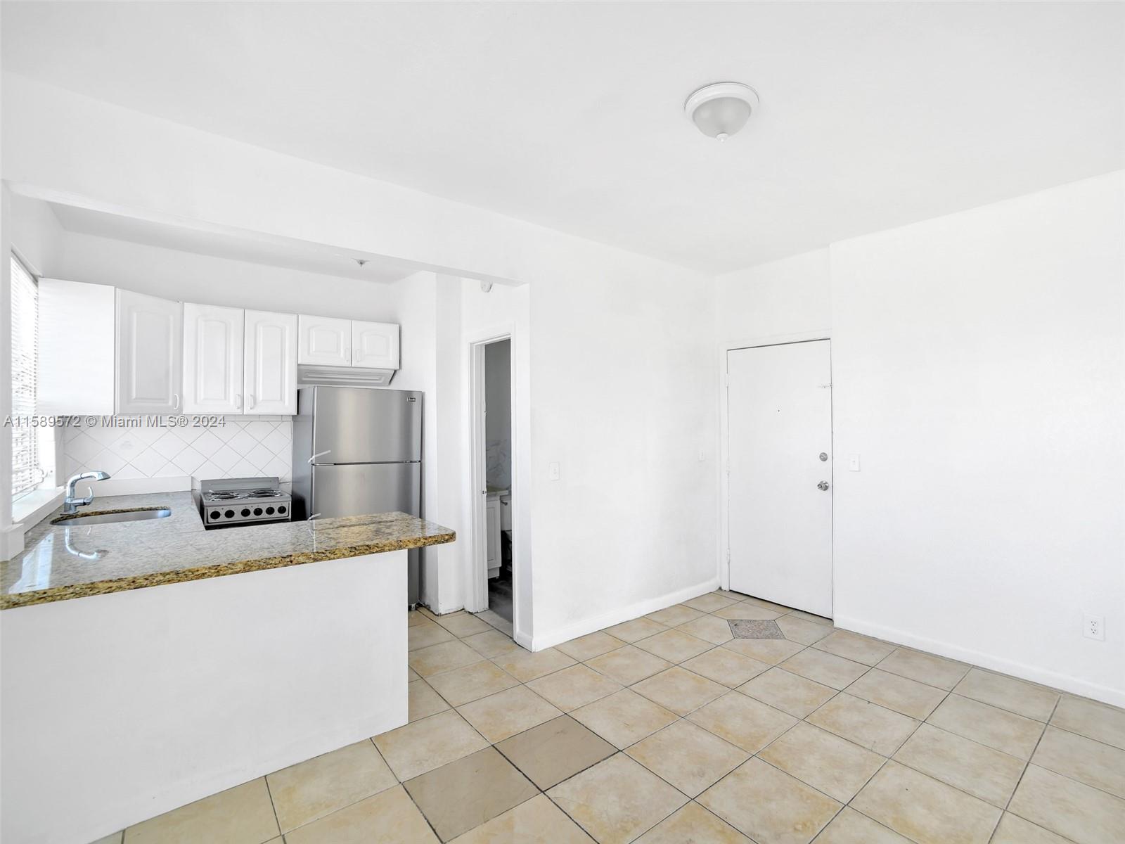 265 East 7th Street Hialeah, FL 33010 - Photo 7 of 28 a large white kitchen with a sink a refrigerator and window