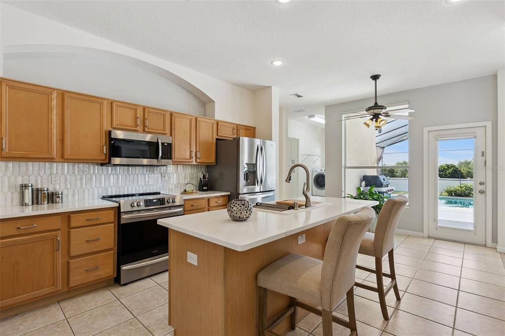 13319 Via Roma Circle Clermont, FL 34711 - Photo 13 of 43 a kitchen with a sink stove cabinets dining table and chairs